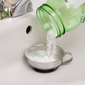 Natural cleaning supplies including baking soda and vinegar for shower drain maintenance