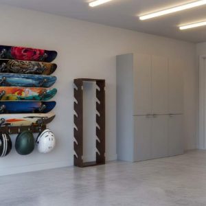 Koutemie 5-layer skateboard wall rack mounted with five colorful decks and helmets on hooks in a modern garage