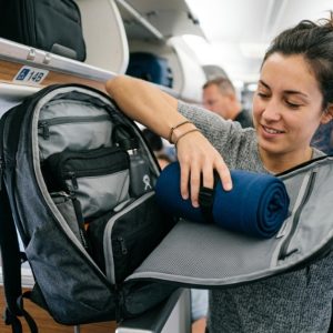 Smiling woman wearing a breathable cooling neck pillow on a flight.