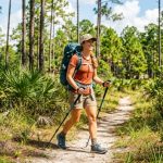 Woman hiking a Florida trail wearing a fitted camping backpack.